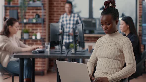 Portrait of African American Coder Sitting Down Writing Programming Language on Laptop Looking Up