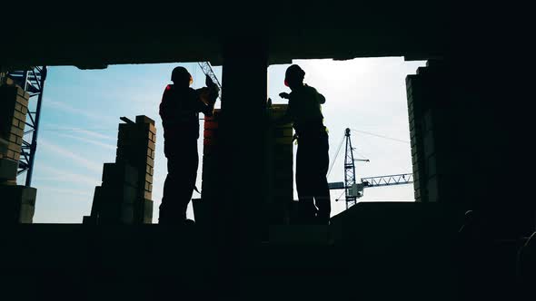 Backlit Masonry Workers Are Making a Brick Wall