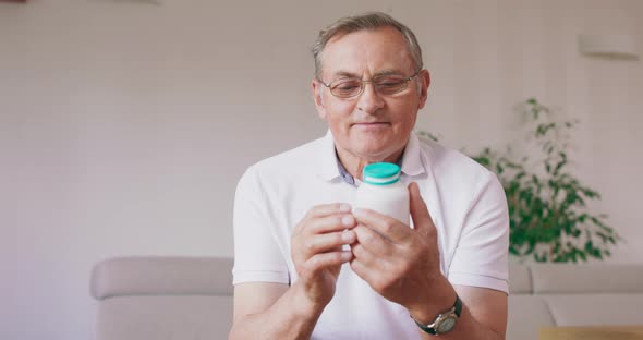 An Older Man Reads the Instructions on the Pill Bottle