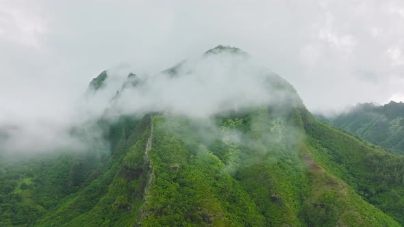 Aerial View Flying Between Rain Clouds Covering Green Mountain Tropical Forest