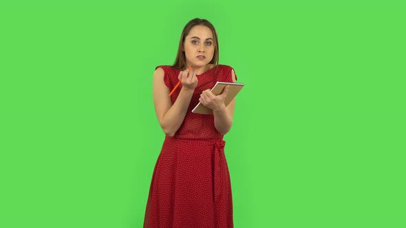 Tender Girl in Red Dress Is Angrily Writing with Pencil in Notebook. Green Screen