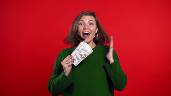 Satisfied Happy Excited Woman Showing Money - U.S. Dollars Banknotes on Red