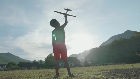 Rural Boy Holding And Looking A Cardboard Airplane