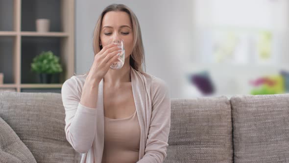 Portrait of Beautiful Young Woman Drinking Refreshing Pure Water Holding Transparent Glass at Home