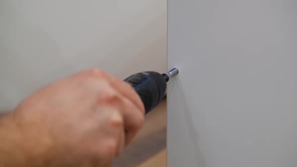 The Worker Screws the Screw Into the Furniture Shape with a Electrical Screwdriver