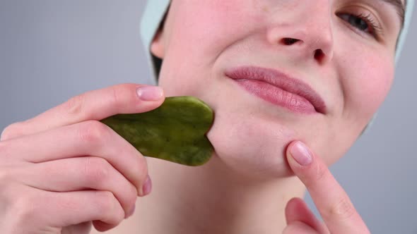 Closeup Portrait of a Young Woman Massaging Her Face with a Gouache Scraper