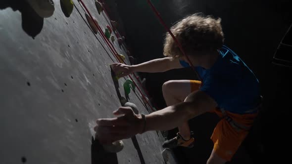 Cinematic Lighting Young Man Professional Climber Training on a Climbing Wall Practicing