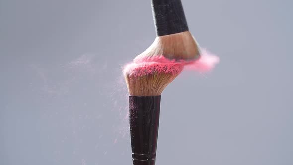 Make-up Brush with Pink Powder Splashes Explosion on Gray Background on Slow Motion