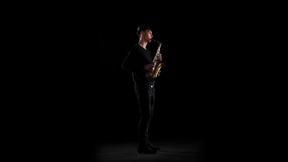 Saxophonist Playing on the Instrument. Black Background in the Studio
