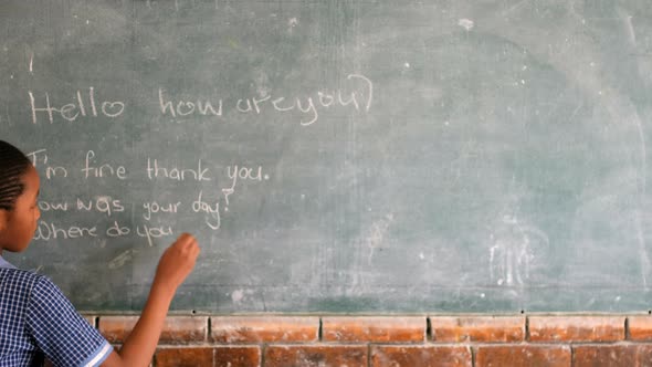 Schoolgirl writing on chalkboard in classroom 4k