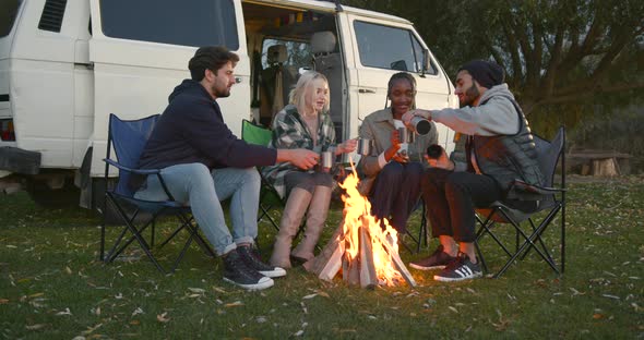 Four Tourists Warm Their Hands By the Fire at the Autumn Camp