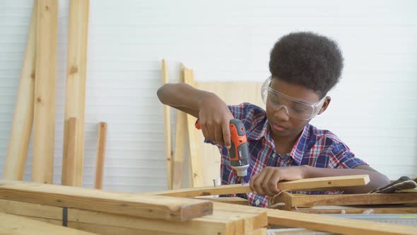 Little child with a drill in hands help dad assembling furniture shelf with power screwdriver tool