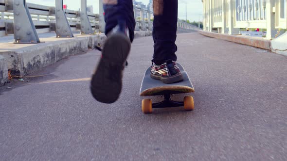 Legs of Guy on Skateboard Who Rides on Bridge