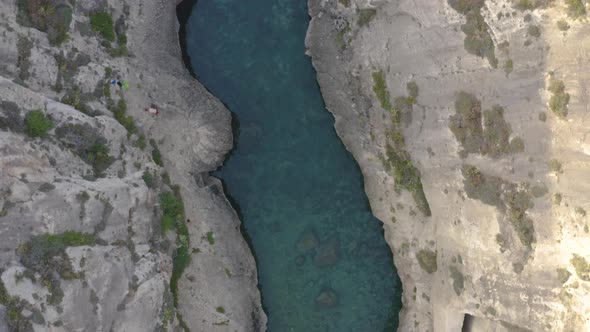 Overhead shot of people swimming in Wied il-Għasri sea canyon,Malta.