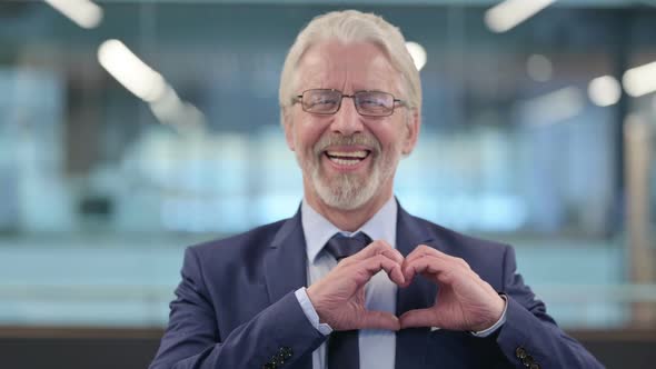 Portrait of Old Businessman Showing Heart Sign By Hand