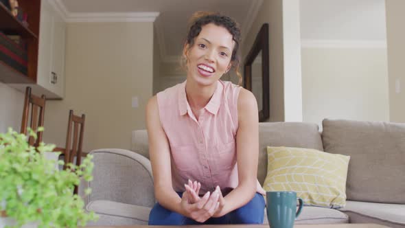 Happy biracial woman sitting on sofa and having video call