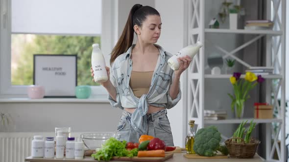 Portrait of Thoughtful Slim Beautiful Young Woman Choosing Soy Milk Vs Cow's Milk and Looking at