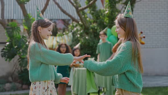 Birthday Girl Reacts at the Gift and Hugs a Friend at a Backyard Party