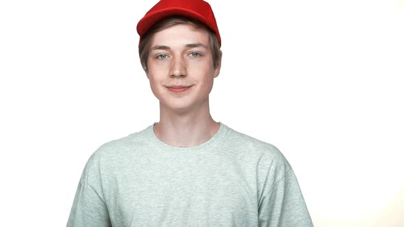 Slow Motion Portrait of Positive Hipster Teenager Wearing Red Cap and Grey Tshirt Smiling Showing