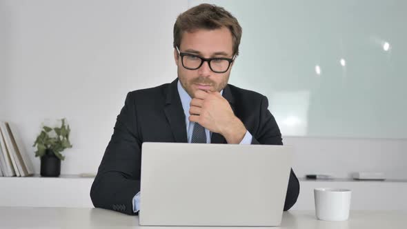 Businessman Thinking and Working on Laptop