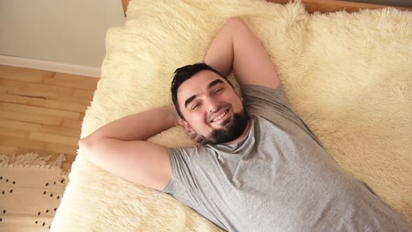 Smiling handsome young man lying on the bed. Home concept.