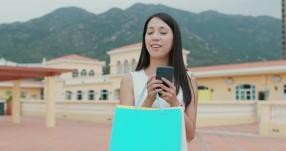 Woman find store with shopping bag abd cellphone at outdoor