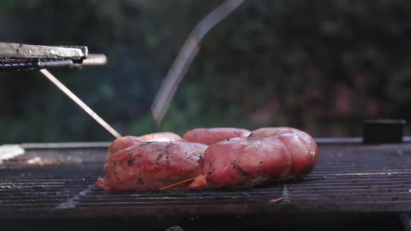 Argentine Asado, Chorizo Sausages cooking on Parilla Grill.