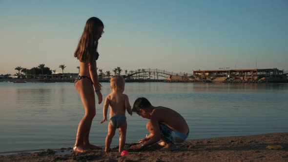 Happy Teenagers Having Fun with Cute Baby Boy on Sand Beach at Sea Resort.