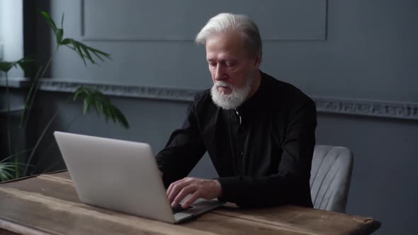 Focused Professional Grayhaired Mature Business Man Using Laptop Sitting at Remote Workplace Desk