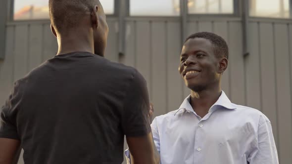 Friendship, greetings. Smiling Black young man greetings in the street-slow motion