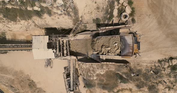 Quarry during work hours with Stone sorting conveyor belts and an open pit mine.