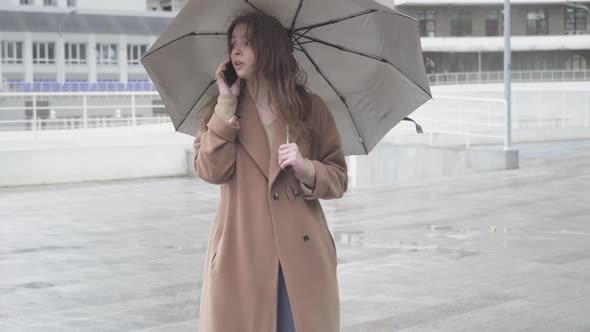 Positive Young Caucasian Woman Talking on the Phone, Waving To Someone and Leaving. Joyful Beautiful