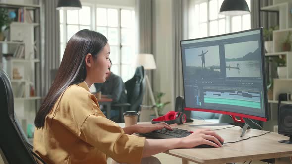 Asian Female Video Editor Works With Footage And Sound On Her Personal Computer In Office