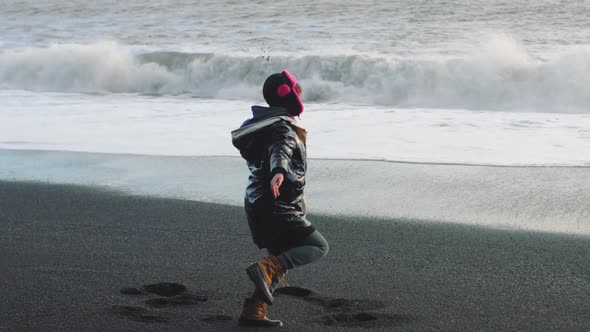 Hipster Woman Spinning Near the Ocean on Volcanic Black Sand Beach in Iceland