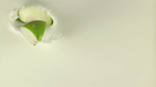 Super Slow Motion Pieces of Fresh Apple Fall Into the Milk with Splashes