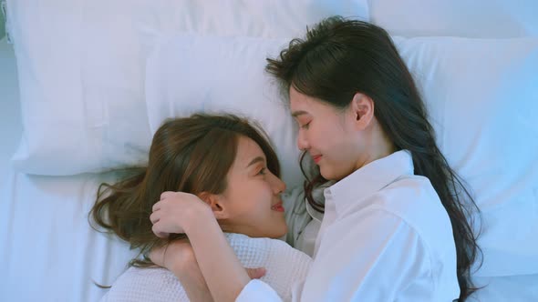 Asian beautiful lesbian couple lying down on bed and hugging each other. Homosexual-LGBTQ concept.