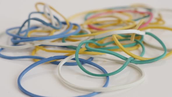 Colorful loops of  rubber on white slow tilt 4K footage