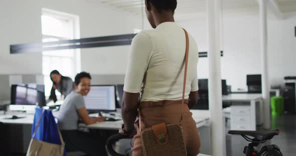 African american businesswoman arriving to office with bike and greeting with business colleagues