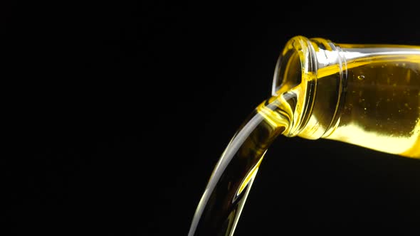 Slow motion shot of extra virgin olive oil being poured out a clear glass bottle