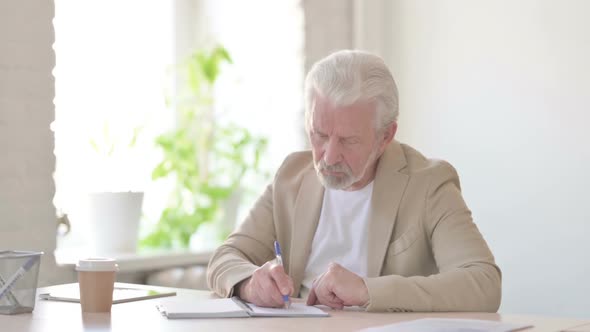 Old Man Writing on Paper in Office