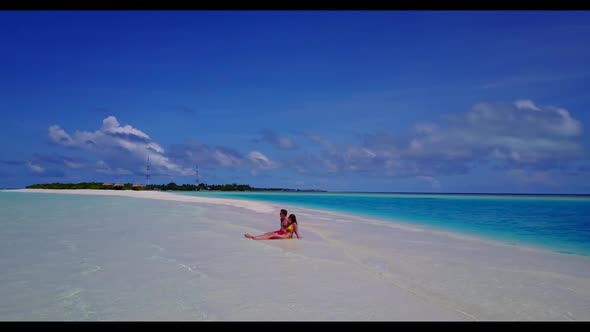 Family of two sunbathe on paradise seashore beach wildlife by blue ocean with white sand background 