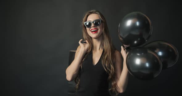 Smiling Woman with Black Balloons and Shopping Bag