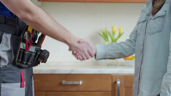 Close Up of Plumber and Client Shaking Hands in Kitchen