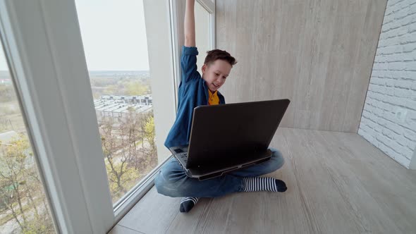 Teen boy plays on the gadget on a balcony