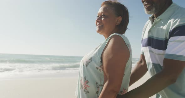 Portrait of smiling senior african american couple embracing on sunny beach