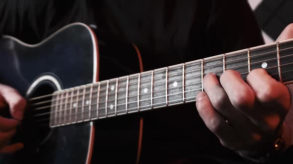 Young Man Playing Acoustic Guitar While Sitting on Sofa in Home Recording Studio