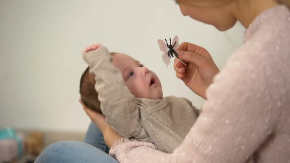 Young Lady Showing Toy Butterfly to Adorable Newborn Baby, Free Time With Child