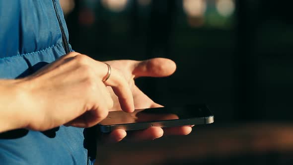 Male Scrolling and Scaling Screen on Smartphone at City Park.