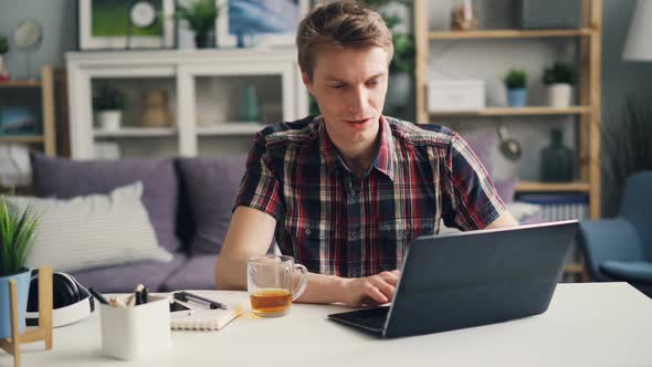 Successful Male Freelancer Is Working at Home Using Laptop Sitting at Desk in Studio