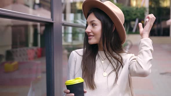 Woman with Long Hair in Trendy Hat which Drinking Fragrant Coffee During Her Walk
